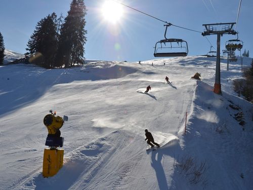 Schneesportler auf der Abfahrt und über ihnen der Sessellift