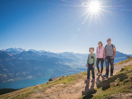 Familie unterwegs auf einem Wanderweg am Niederhorn mit Blick auf den Thunersee