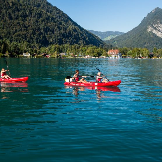 Gruppe mit roten Kajaks von Mountainsurf auf dem blauen Thunersee im Sommer