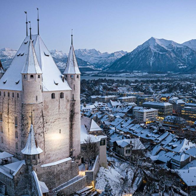 Das Schloss Thun und die Stadt mit verschneiten Dächern an einem Winterabend