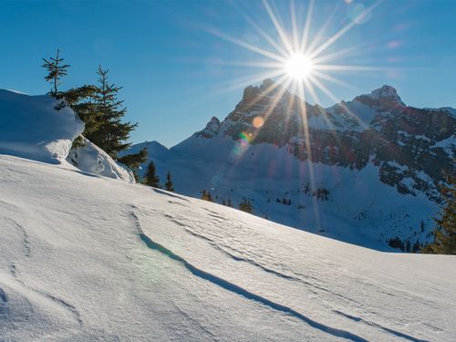 Verschneite Alplandschaft mit der Wintersonne am Horizont