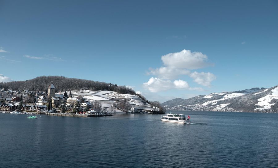 Schiff auf dem blauen Thunersee in der verschneiten Winterlandschaft