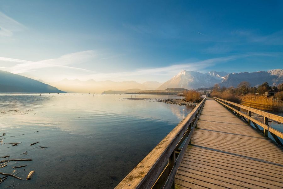 Atemberaubender Sonnenaufgang über dem Thunersee an einem Wintermorgen – ein Spazierweg führt über einen Holzsteg