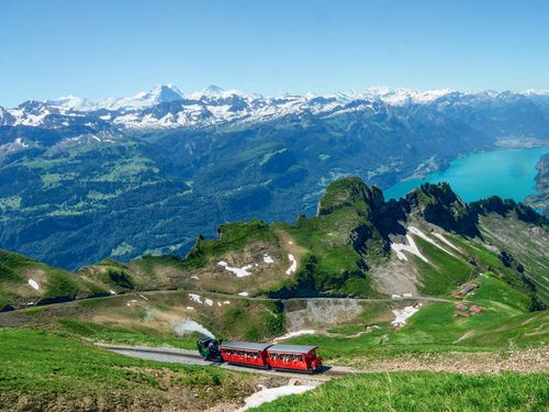 Dampfende, rote Brienz Rothorn Bahn mit Blick auf den Brienzersee und die umliegenden Bergketten