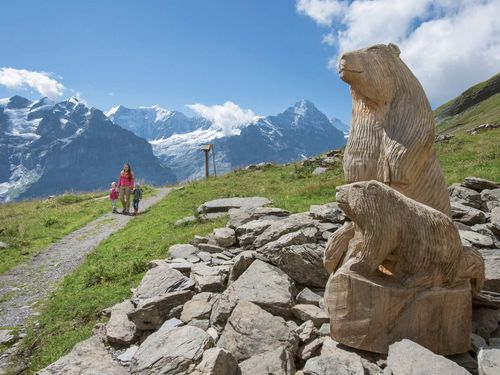 Familie auf dem Murmeltier Lehrpfad auf der First ob Grindelwald mit Blick auf Murmeltier aus Holz