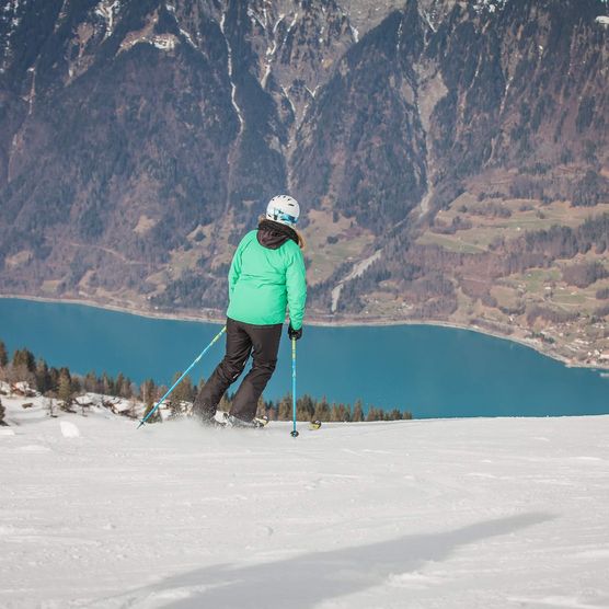 Skifahrer im Skigebiet auf der Axalp mit Blilcka uf den türkisen Brienzersee und Brienz